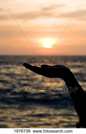 Stock Photo - Thailand, Phuket, Golden Sunset Silhouette Of Hand Supporting Soft Focus Sunset.. Fotosearch