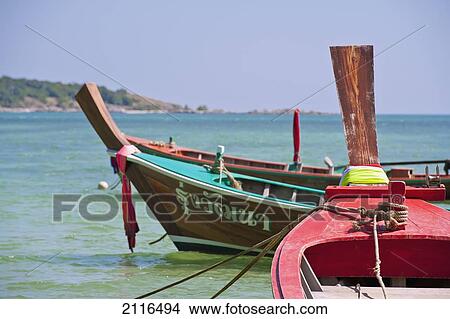 Picture - Thailand, Phuket, Rawaii Beach, Close up of longtail boats along the shoreline, Land in distance.. Fotosearch