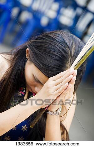Stock Photograph - Thailand, Portrait of woman praying; Bangkok. Fotosearch