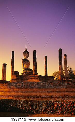Thailand, Sukhothai, Glowing sunlight on structure of Buddha statue with many pillars at sunset; Wat Mahathat View Large Photo Image Stock Photography - Thailand, Sukhothai, Glowing sunlight on structure of Buddha statue with many pillars at sunset; Wat Mahathat. Fotosearch