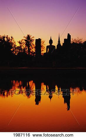 Thailand, Sukhothai, Wat Mahathat, Distant View Of Buddha Statue At Sunset, Silhouetted And Reflecting On Water. View Large Photo Image Stock Photograph - Thailand, Sukhothai, Wat Mahathat, Distant View Of Buddha Statue At Sunset, Silhouetted And Reflecting On Water.. Fotosearch