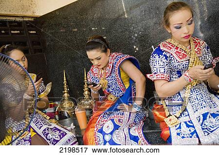 Stock Photo - Thailand, Thai Dancers On Phone In Erawan Shrine; Bangkok. Fotosearch