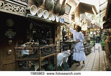 Stock Image - Thailand, Woman looking at items for sale; Chiang Mai, Antique outdoor shopping mall. Fotosearch