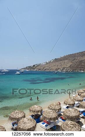 Stock Photograph - Thatched umbrellas on Ornos Beach; Mykonos Town, Mykonos, The Cyclades, The Greek Islands, Greece. Fotosearch