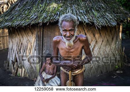 Stock Photo - The chief of Yakel Village, with his wife in the background; Tanna Island, Vanuatu. Fotosearch