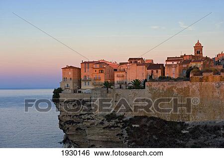 Stock Photograph - The first rays of sunlight hitting the medieval fortified town of Bonifacio. Corsica. France.. Fotosearch