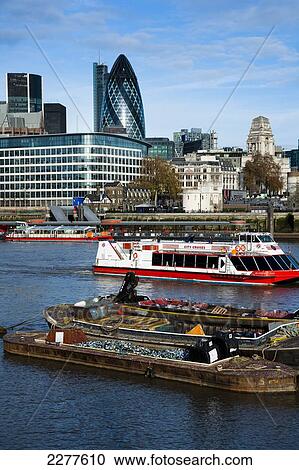 The Gherkin building dominates the skyline with tourists boats and scrap barges on the Thames; London, England View Large Photo Image Stock Image - The Gherkin building dominates the skyline with tourists boats and scrap barges on the Thames; London, England. Fotosearch