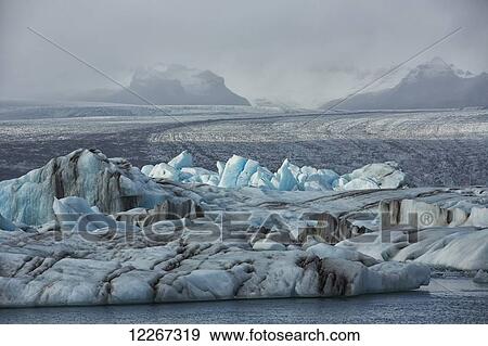 The glacial lagoon Jokulsarlon is full of icebergs waiting to be washed out to the ocean on the south coast of Iceland; Iceland View Large Photo Image Stock Photo - The glacial lagoon Jokulsarlon is full of icebergs waiting to be washed out to the ocean on the south coast of Iceland; Iceland. Fotosearch