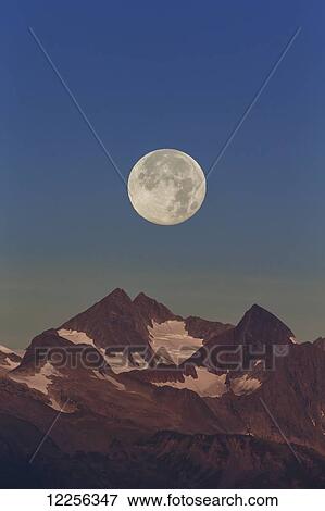 Stock Photo - The Harvest Moon (September Moon) rises above the Chilkat mountains near Juneau, Southeast Alaska. Fotosearch