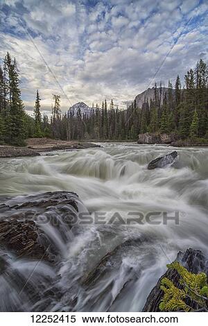 The Kicking Horse River flows over a waterfall before it goes beneath a natural bridge, Yoho National Park; British Columbia, Canada View Large Photo Image Stock Photography - The Kicking Horse River flows over a waterfall before it goes beneath a natural bridge, Yoho National Park; British Columbia, Canada. Fotosearch