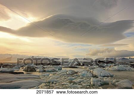 The Melting Icebergs Of Jokulsarl On The Glacial Lagoon In Southern Iceland With Lenticular Clouds Above Them View Large Photo Image Stock Photo - The Melting Icebergs Of Jokulsarl On The Glacial Lagoon In Southern Iceland With Lenticular Clouds Above Them. Fotosearch