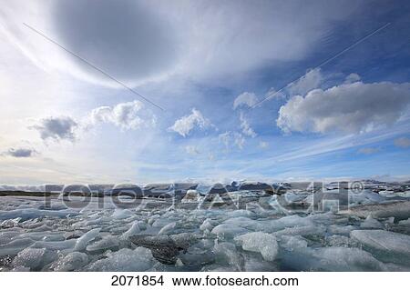 The Melting Icebergs Of Jokulsarlon, The Glacial Lagoon In Southern Iceland With Lenticular Clouds Above Them View Large Photo Image Picture - The Melting Icebergs Of Jokulsarlon, The Glacial Lagoon In Southern Iceland With Lenticular Clouds Above Them. Fotosearch