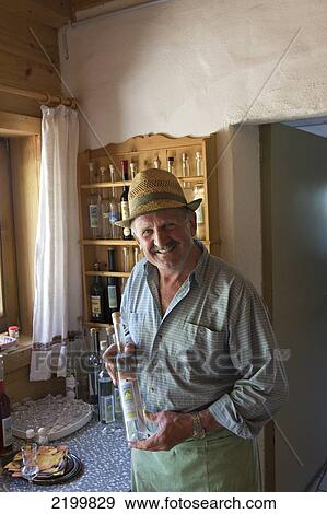 Stock Photo - The owner of Lammerbichlalm farm complex and inn at Lammerbuhelalm holding a bottle of his home made schnapps. Lammerbuhealm. Kitzbuehel. Austria. Fotosearch