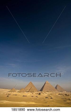 Stock Image - The Pyramids With People On Camels; Cairo, Egypt, Africa. Fotosearch