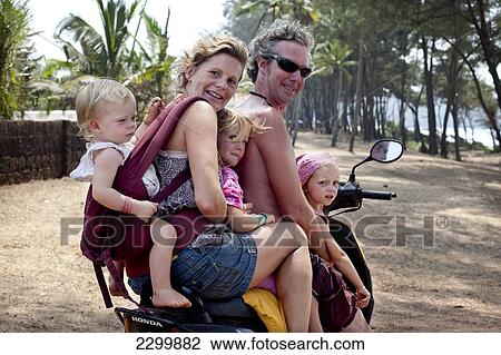 Stock Image - The Reynolds family on holiday in Goa transport the family Indian style 5-up on a moped, Turtle Beach, Goa, India.. Fotosearch