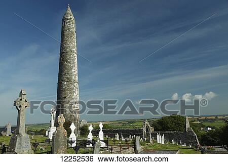 Stock Photograph - The round tower and ruins of the cathedral in Ardmore village; Ardmore, County Waterford, Ireland. Fotosearch