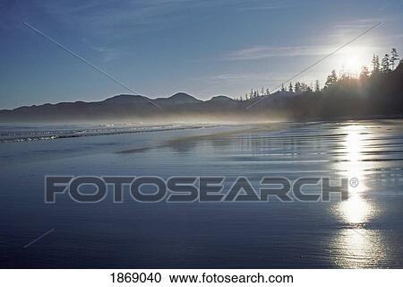 The Setting Sun Shines On The Wet Beach As The Waves Roll In To Shore View Large Photo Image Stock Image - The Setting Sun Shines On The Wet Beach As The Waves Roll In To Shore. Fotosearch