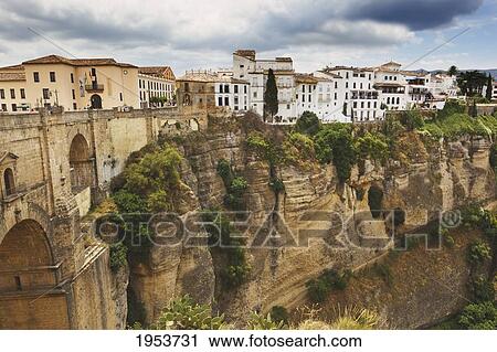 Stock Image - The Town Perched On The Gorge With New Bridge On The Left; Ronda Malaga Andalusia Spain. Fotosearch