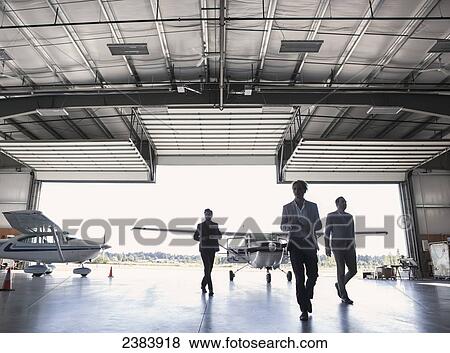 Stock Photo - Three businessmen entering airplane hangar; Langley, British Columbia, Canada. Fotosearch