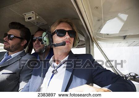 Stock Photo - Three businessmen sitting in an airplane; Langley, British Columbia, Canada. Fotosearch