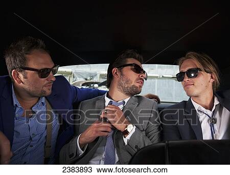 Stock Image - Three businessmen sitting in the backseat of a car; Langley, British Columbia, Canada. Fotosearch
