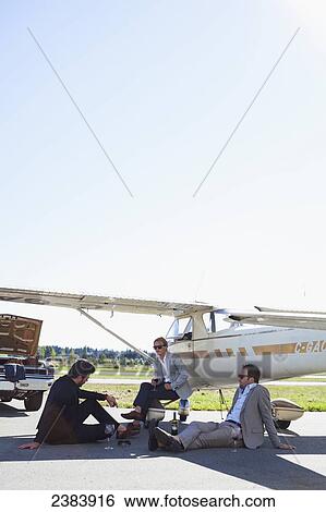 Stock Photograph - Three businessmen waiting by airplane; Langley, British Columbia, Canada. Fotosearch