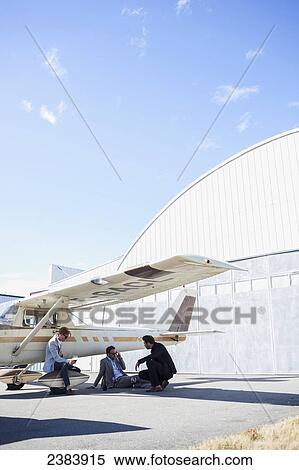 Stock Photography - Three businessmen waiting by airplane; Langley, British Columbia, Canada. Fotosearch