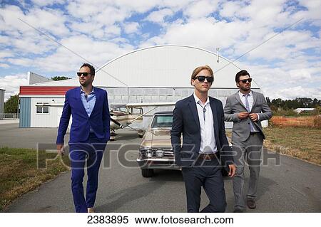 Three businessmen walking away from a car and airplane hangar; Langley, British Columbia, Canada View Large Photo Image Stock Photography - Three businessmen walking away from a car and airplane hangar; Langley, British Columbia, Canada. Fotosearch