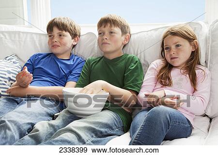 Three Children Sitting On A Couch Presumably Watching Tv; San Francisco, California, Usa View Large Photo Image Stock Photo - Three Children Sitting On A Couch Presumably Watching Tv; San Francisco, California, Usa. Fotosearch