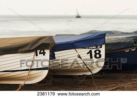 Stock Photo - Three covered fishing boats in front of the sea; Shaldon, Devon, England. Fotosearch