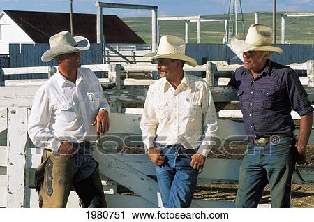 Three Cowboys Leaning Against /Nwhite Fence Near Stables, Wearing Long Sleeve Shirts, Jeans And Cowboy Hats. View Large Photo Image Stock Image - Three Cowboys Leaning Against /Nwhite Fence Near Stables, Wearing Long Sleeve Shirts, Jeans And Cowboy Hats.. Fotosearch