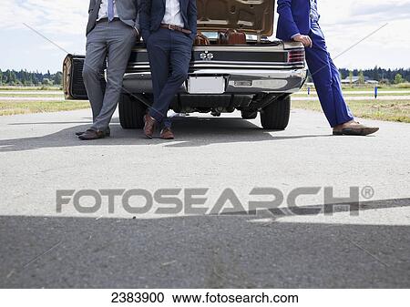 Three men in suits leaning against a car with an open trunk; Langley, British Columbia, Canada View Large Photo Image Stock Image - Three men in suits leaning against a car with an open trunk; Langley, British Columbia, Canada. Fotosearch