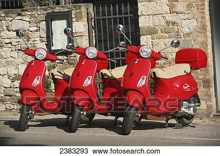 Stock Image - Three red vespa scooters for hire parked in Radda in Chianti; Tuscany, Italy. Fotosearch