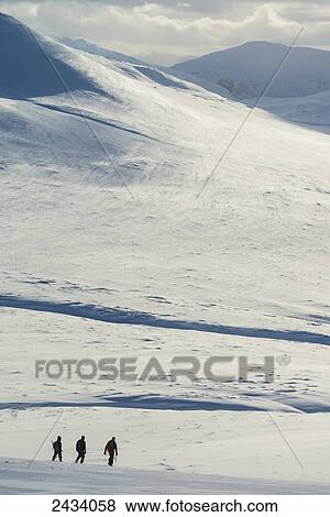 Stock Photo - Three walkers on snowy, winter walk descending Creag Pitridh, near Laggan; Scotland. Fotosearch