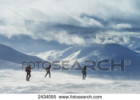 Stock Photography - Three walkers on snowy, winter walk ascending Geal Charn, near Laggan; Scotland. Fotosearch