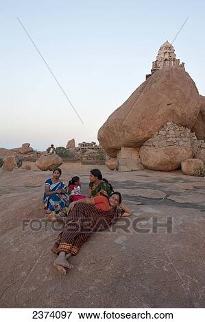 Three women and a girl sit on a rock surface overlooking the landscape; Hampi, Karnataka, India View Large Photo Image Stock Photo - Three women and a girl sit on a rock surface overlooking the landscape; Hampi, Karnataka, India. Fotosearch