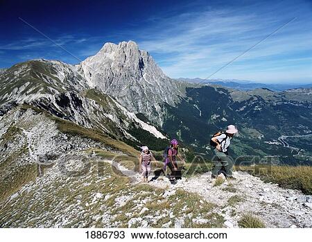Stock Image - Three Women Walking Along Ridge In Front Of Corno Grande In The Campo Imperatore. Fotosearch