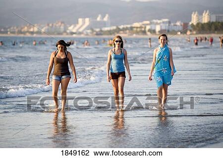 Stock Image - Three Women Walking On The Shoreline Of A Beach; Puerto Vallarta, Mexico. Fotosearch