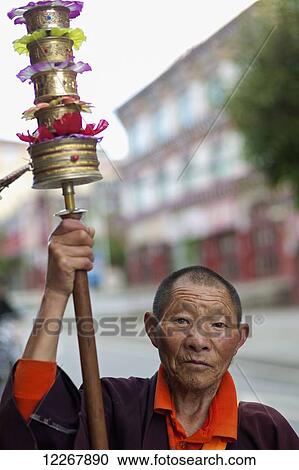 Stock Image - Tibetan man spins prayer wheel; Garze, Sichuan, China. Fotosearch