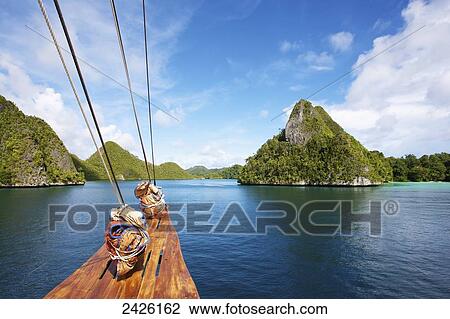 Stock Image - Tiger Blue Phinisi Schooner sailing through Pulau Wayag Islands of Raja Ampat; Indonesia. Fotosearch