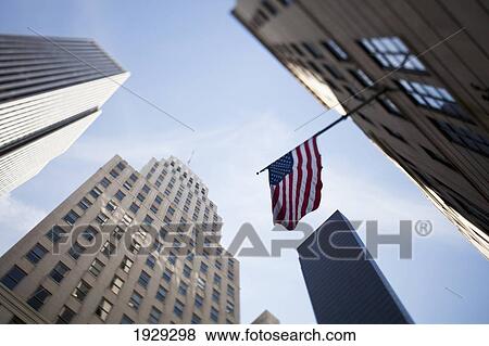 Stock Photo - Tilt shift lens image - looking up at Sykscrapers with Stars and Stripes flag in Manhattan, New York. USA.. Fotosearch
