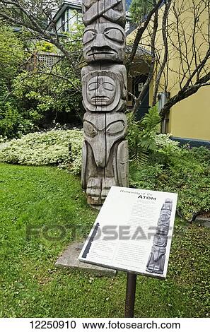 Stock Image - Tlingit totem pole named Harnessing the Atom, carved by Amos Wallace, in western red cedar in front of Juneau-Douglas City Museum; Juneau, Alaska, United States of America. Fotosearch