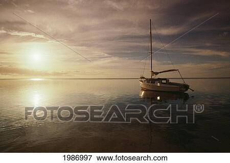 Tonga, Boat anchored in peaceful surroundings and sunrise with glassy reflections on ocean; Atata View Large Photo Image Stock Photo - Tonga, Boat anchored in peaceful surroundings and sunrise with glassy reflections on ocean; Atata. Fotosearch