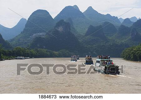 Stock Image - Tour Boats On River Li Near Yangshuo, With Karst Formations In The Background; Guilin, Guangxi, China. Fotosearch