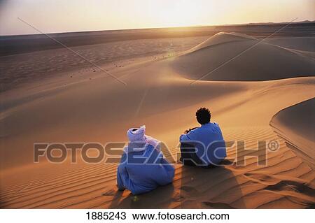 Stock Image - Tourist And Berber Sunset Sand Dunes. Fotosearch