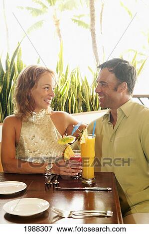 Stock Photo - Tourist Couple At An Island Style Bar Enjoying Cocktails. Fotosearch