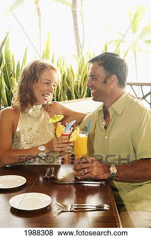 Stock Photo - Tourist Couple At An Island Style Bar Enjoying Cocktails. Fotosearch