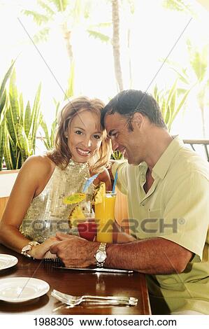 Stock Photography - Tourist Couple At An Island Style Bar Enjoying Cocktails. Fotosearch
