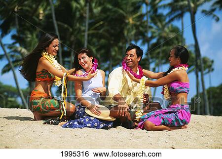 Tourist Couple Sit On Beach, Two Hawaiian Women Welcome Them With Leis View Large Photo Image Stock Photograph - Tourist Couple Sit On Beach, Two Hawaiian Women Welcome Them With Leis. Fotosearch