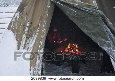 Stock Photo - Tourist In Front Of The Fire In Kota Of Saami Under A Wooden Teepee, Levi, Lapland, Finland. Fotosearch